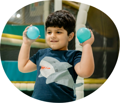 Smiling child holding soft play balls in supervised indoor play area at Piccoli.