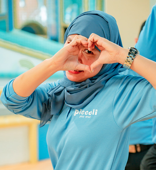 Piccoli team member making heart gesture during supervised play session.
