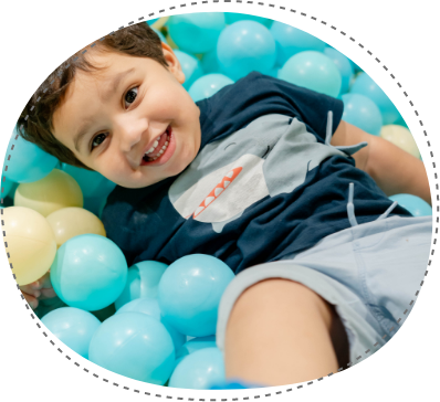 Happy child playing in pastel ball pit at Piccoli indoor play area.