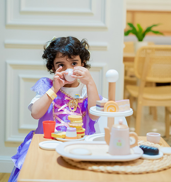 Child in princess costume enjoying pretend tea party role-play at Piccoli.