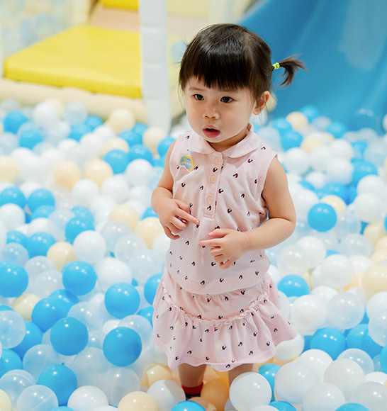 Toddler standing in pastel ball pit at Piccoli indoor play area.