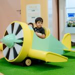 Young child playing in airplane-themed role-play area at Piccoli indoor play space.