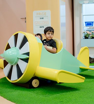 Young child playing in airplane-themed role-play area at Piccoli indoor play space.