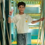 Smiling child giving peace sign while playing in supervised indoor soft play area at Piccoli.