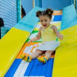 Young child sliding down colorful soft play slide at Piccoli indoor play space.