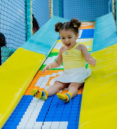 Young child sliding down colorful soft play slide at Piccoli indoor play space.
